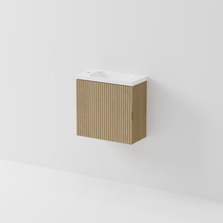 A modern wall-mounted bathroom vanity with a fluted light brown wood cabinet and a white ceramic sink basin, shown against a clean white wall.