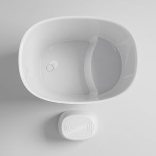 A minimalist white freestanding bathtub with a built-in curved divider and a matching white rectangular soap dish below, shown from a top-down perspective on a light gray background.
