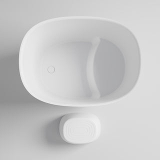 White freestanding bath and stool on a light grey background