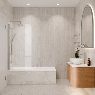 A modern bathroom interior with a built-in bathtub, glass shower screen, light beige tiled walls, a floating wood vanity, white vessel sink, and a large arched illuminated mirror.